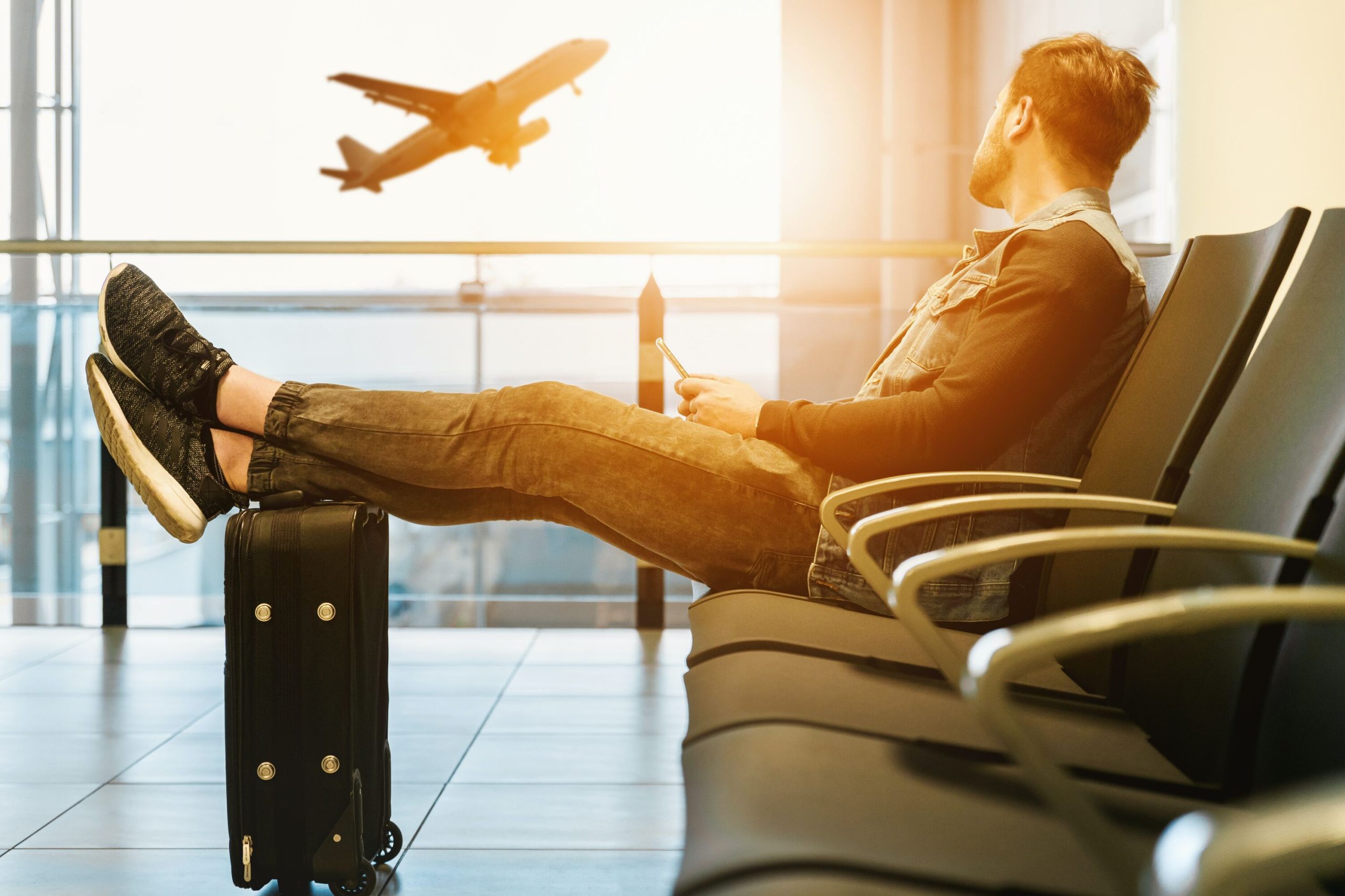 homem olhando no aeroporto avião com os pés sobre mala de viagem