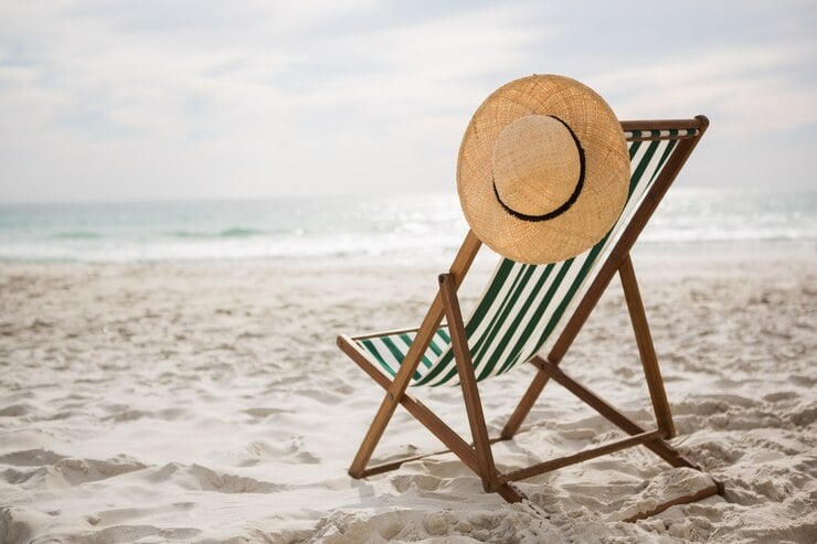 Chapéu de palha mantidos em cadeira de praia vazia
