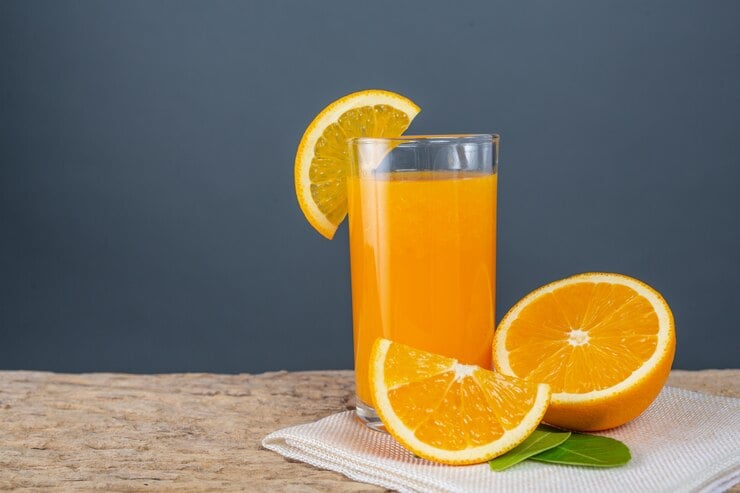 Vidro do suco de laranja colocado num copo sobre madeira