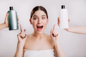 Mulher de cabelo liso castanho apontando para dois shampoos sem rótulo