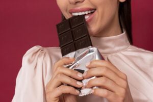 Mulher comendo chocolate e sorrindo