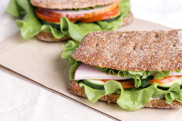 Sanduíche natural de pão integral com alface, peito de peru, pepino e tomate
