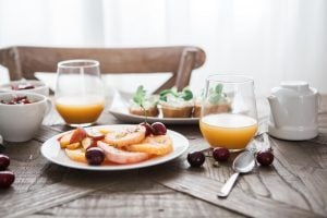 café da manhã com prato de frutas e dois copos de suco sobre a mesa