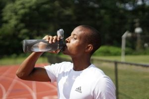 homem bebendo água numa pista de atletismo